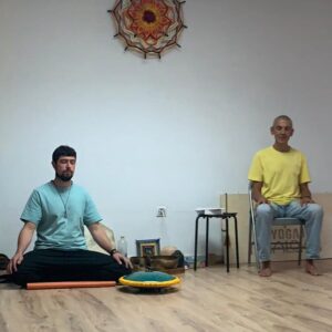 Quique Moreiras y un alumno meditando en una clase de mindfulness una sentada en una banqueta y la otra en posición de loto en una esterilla